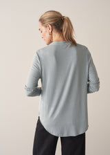 Woman wearing long sleeve pale blue top with black wide leg trousers