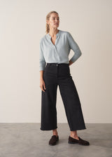 Woman wearing long sleeve pale blue top with black wide leg trousers