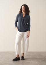 Woman wearing dark grey long sleeve top and white barrel leg jeans