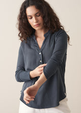 Woman wearing dark grey long sleeve top and white barrel leg jeans