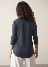 Woman wearing dark grey long sleeve top and white barrel leg jeans