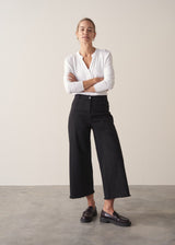 Woman wearing white long sleeve top with black trousers