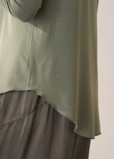Woman wearing a moss green long-sleeve jersey top against a plain background