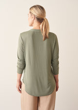 Woman wearing a sage green long sleeve top with beige wide leg cropped trousers