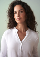 Woman wearing a long sleeve white top with button detail