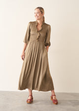 A woman wearing a light khaki green olive satin midi dress with smocked detail and ruffle collar