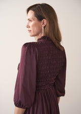 Woman wearing a plum sati midi dress standing against a plain background