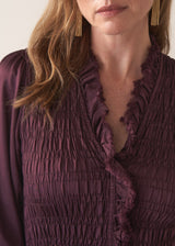 Woman wearing a plum sati midi dress standing against a plain background