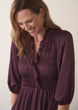 Woman wearing a plum sati midi dress standing against a plain background
