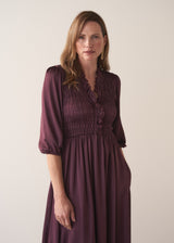 Woman wearing a plum sati midi dress standing against a plain background
