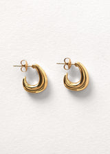 Chunky gold structured hoop earrings on a beige background