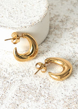 Chunky gold structured hoop earrings on cement background