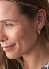 Woman wearing gold structured hoop earrings