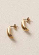 Side view of pair of brushed gold stud earrings in the shape of a teardrop, on beige background