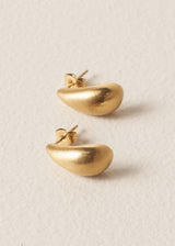 Pair of brushed gold stud earrings in the shape of a teardrop, on beige background
