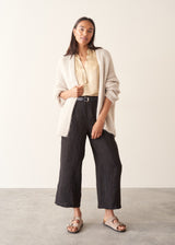 A woman wearing a short-sleeve yellow gold blouse and black trousers.