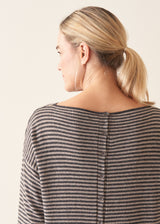 Woman wearing beige and grey stripe sweater with button back and beige cropped trousers