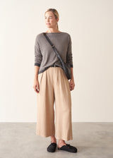 Woman wearing beige and grey stripe sweater with button back and beige cropped trousers