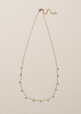 Gold chain necklace with small bead detailing on beige background