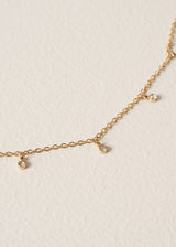 Close up of gold chain necklace with small bead detailing on beige background
