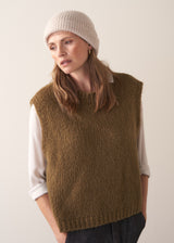 Woman wearing a cream, super soft, alpaca wool blend beanie hat, styled with khaki sweater and dark jeans