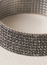 Close up of bracelet cuff with grey diamantes on beige background