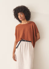 Woman wearing a light brown knitted top with a cream linen maxi skirt.