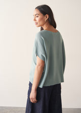 Woman wearing light sage sweater with blue jeans