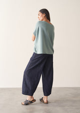 Woman wearing light sage sweater with blue jeans
