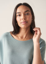 Woman wearing light sage sweater with blue jeans