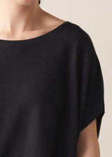 Woman wearing black relaxed sleeve sweater and white barrel leg jeans