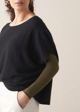 Woman wearing black relaxed sleeve sweater and white barrel leg jeans