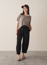 Woman wearing light stone sleeveless knit sweater with black jersey trousers