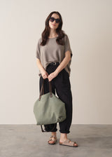 Woman wearing light stone sleeveless knit sweater with black jersey trousers