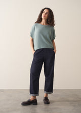 Woman wearing sage short sleeve draped sweater with blue jeans