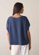 Woman wearing a navy blue sleeveless sweater and white barrel leg jeans