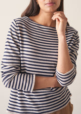 Woman wearing dark grey and off white stripe knit sweater and brown linen trousers