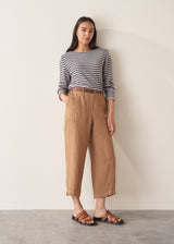 Woman wearing dark grey and off white stripe knit sweater and brown linen trousers