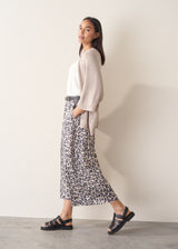 Woman wearing greige open knit relaxed cardigan and leopard print torusers