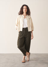 Woman wearing light cream devoree jacquard textured shirt and green trousers