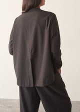 A woman wearing a dark check boxy jacket with barrel leg check trousers and a white t-shirt.