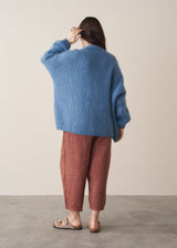 Woman wearing chunky blue cardigan and brown linen trousers