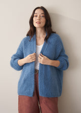 Woman wearing chunky blue cardigan and brown linen trousers