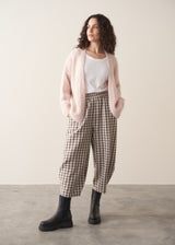 Woman wearing an oversized blush pink chunky knit cardigan with checked trousers and black boots