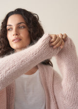 Woman wearing an oversized blush pink chunky knit cardigan with white t-shirt