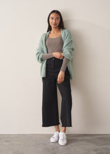 Woman wearing cashmere-blend long sleeve stripe top and black wide leg cropped trousers.