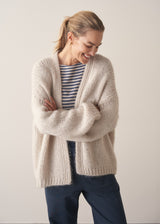 Woman wearing oversized chunky cardigan in oatmeal with dark grey blue joggers and stripe knit top