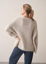 Woman wearing oversized chunky cardigan in oatmeal with dark grey blue joggers and stripe knit top