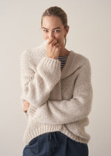 Woman wearing oversized chunky cardigan in oatmeal with dark grey blue joggers and stripe knit top