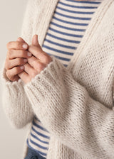 Woman wearing oversized chunky cardigan in oatmeal with dark grey blue joggers and stripe knit top